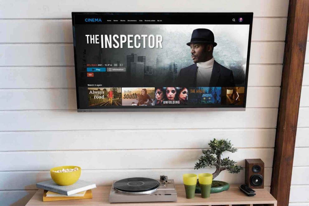 Un televizor afișează filmul 'The Inspector' într-o sufragerie cu un pick-up și decorațiuni