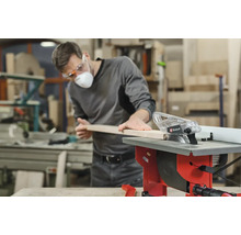 Un bărbat taie o scândură de lemn cu un ferăstrău circular de masă Einhell într-un atelier.