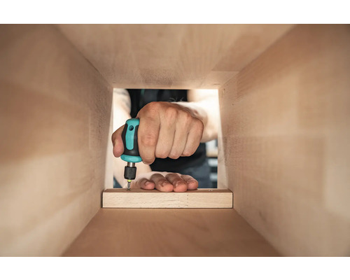 O persoană înșurubează o scândură de lemn cu o șurubelniță