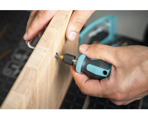 Bărbat înșurubând un mâner pe o scândură de lemn cu o șurubelniță