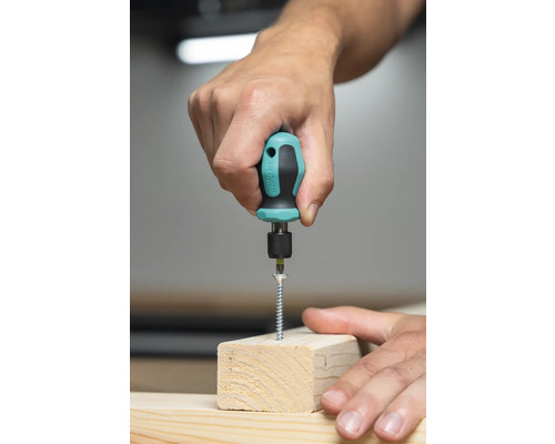 O persoană înșurubează un șurub într-o bucată de lemn cu o șurubelniță