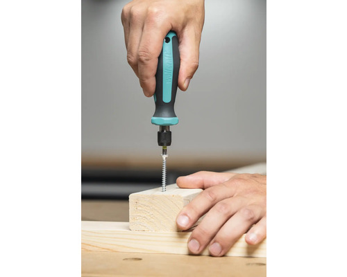 O persoană înșurubează un șurub într-o bucată de lemn cu o șurubelniță.