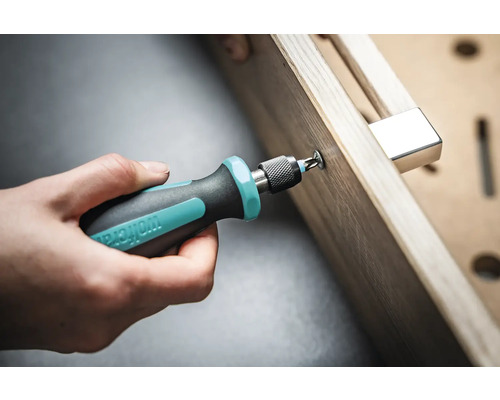 O mână înșurubează un șurub cu o șurubelniță într-o piesă de lucru.