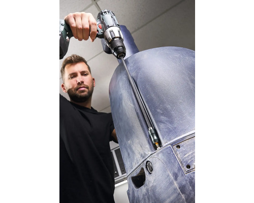 Un bărbat înșurubează o componentă din plastic cu o șurubelniță electrică.