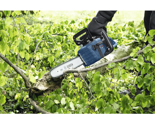 O persoană taie o ramură cu un motoferăstrău Bosch.