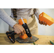 Persoană care lipește o lumânare cu un pistol de lipit pe un suport