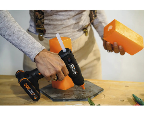 Persoană care lipește o lumânare cu un pistol de lipit pe un suport