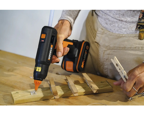 Baston de lipici cu acumulator care atașează o clamă de rufe pe o bucată de lemn