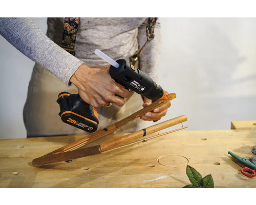 O persoană lipește bețe de bambus cu un pistol de lipit fără fir.