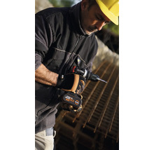 Bărbat cu cască de construcție galbenă folosind o șurubelniță cu acumulator