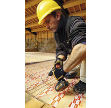 Meseriaș cu cască de protecție și șurubelniță cu acumulator instalând plăci izolatoare pe o podea de lemn.