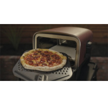 Pizza pe o paletă de pizza în fața unui cuptor de pizza