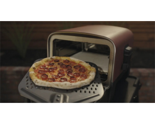 Pizza pe o paletă de pizza în fața unui cuptor de pizza