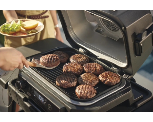 Grătar electric cu mai multe chiftele de burger pe grătar.