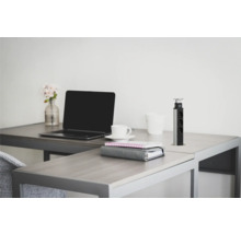 Birou cu laptop, ceașcă de cafea, blocnotes și coloană retractabilă de prize pe un birou.