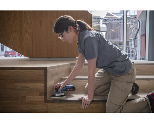 Femeie șlefuind scara din lemn cu o mașină de șlefuit