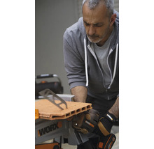 Un bărbat taie o cărămidă cu un ferăstrău de masă Worx.