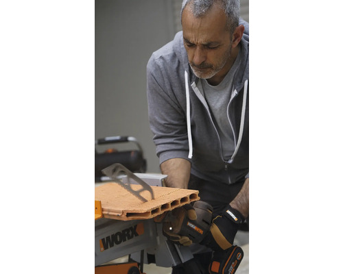 Un bărbat taie o cărămidă cu un ferăstrău de masă Worx.