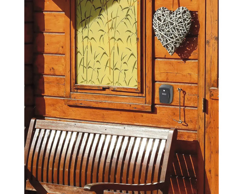 Cutie de chei cu cod numeric pe un perete de lemn lângă o bancă de lemn