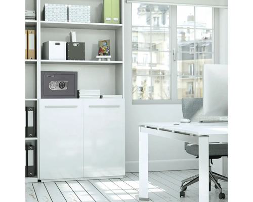 Un birou luminos cu un raft alb, un birou și un seif gri