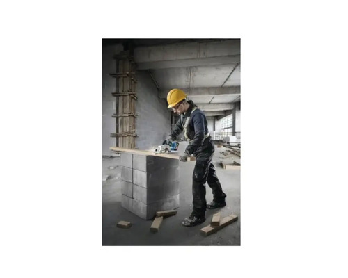 Un meșter cu cască de protecție taie o scândură de lemn cu un ferăstrău circular.