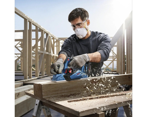 Artizan care folosește un rindel electric Bosch pentru a rindelui o bucată de lemn.