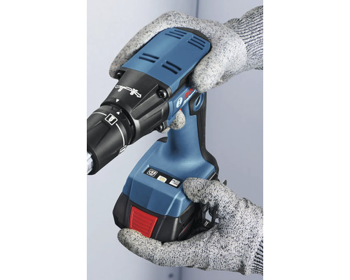 O persoană cu mănuși ține o șurubelniță electrică pentru gips-carton.