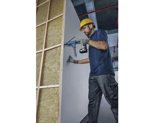 Meseriaș fixează o placă de gips-carton cu o șurubelniță cu magazie pe un perete