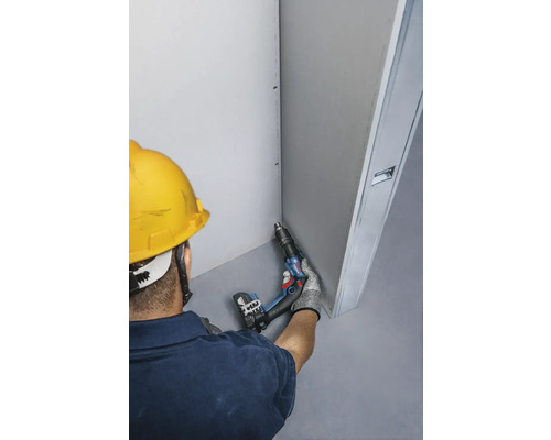 Artizan cu șurubelniță electrică efectuând lucrări de gips-carton