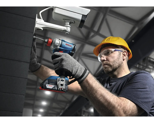 Un bărbat cu ochelari de protecție și cască de protecție fixează o cameră de supraveghere cu o șurubelniță cu impact cu acumulator de la Bosch.