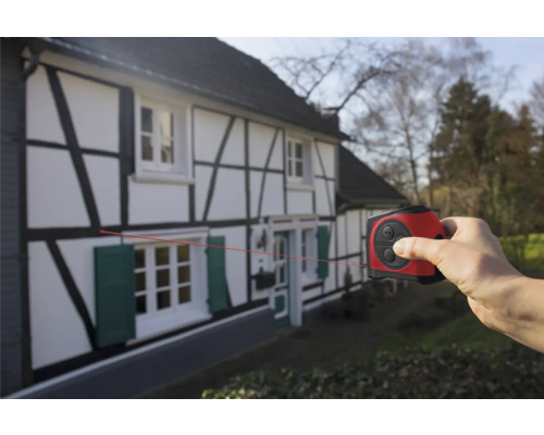 Mână care folosește un telemetru laser pe o casă cu cadre din lemn