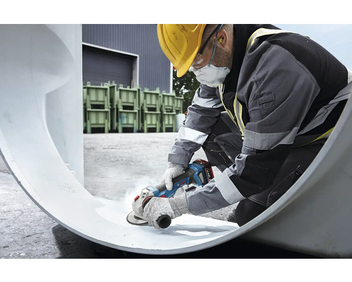 Un muncitor în construcții prelucrează o țeavă cu un polizor unghiular