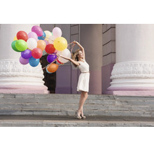 Femeie cu multe baloane în fața unei clădiri