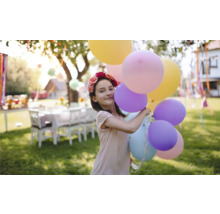 Fată cu coroană de flori și baloane în grădină pentru o petrecere în grădină