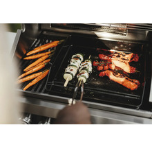 Legume precum morcovi, frigărui de dovlecei și roșii sunt preparate pe un grătar.