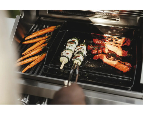 Legume precum morcovi, frigărui de dovlecei și roșii sunt preparate pe un grătar.