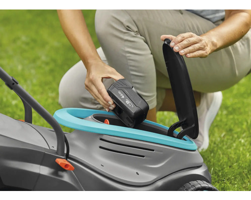 O persoană introduce o baterie de 4,0 Ah într-o mașină de tuns iarba