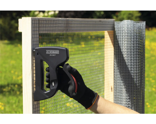 O persoană fixează plasă de sârmă pe un cadru de lemn cu ajutorul unui capsator J.C. Schwarz JCS-530 P