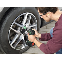 Bărbat schimbând o anvelopă la o mașină cu o cheie de impact fără fir