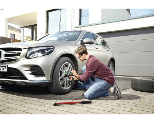 Un bărbat schimbă o anvelopă la o mașină cu o cheie de impact.