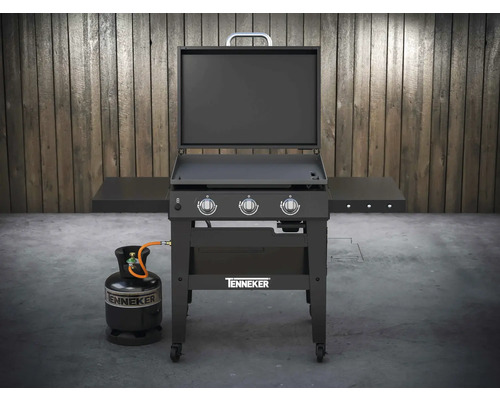 Cărucior grătar pe gaz Tenneker cu butelie de gaz în fața unui perete de lemn
