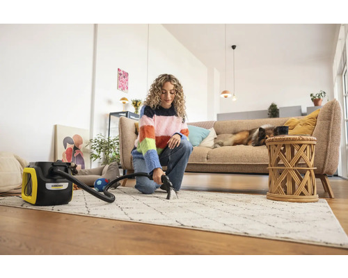 Femeie curăță covorul cu un aspirator cu injecție-extracție Kärcher într-un living luminos