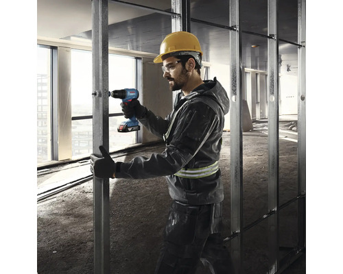 Un bărbat fixează o structură metalică cu o șurubelniță electrică.