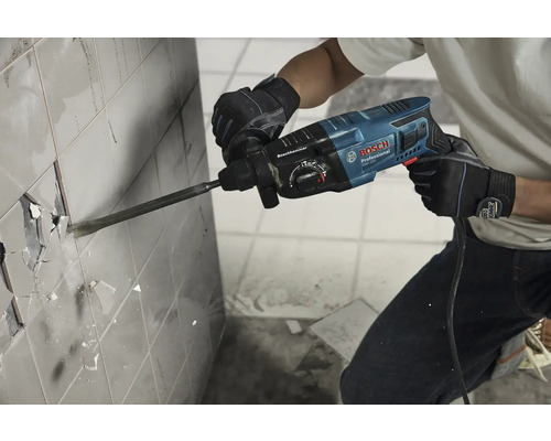 O persoană îndepărtează plăci cu un ciocan rotopercutor marca Bosch