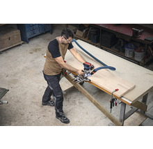 Un bărbat lucrează cu o freză verticală pe o piesă de prelucrat pe un banc de lucru într-un atelier.