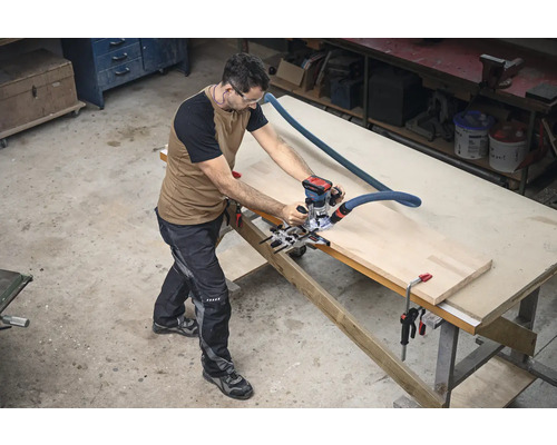 Un bărbat lucrează cu o freză verticală pe o piesă de prelucrat pe un banc de lucru într-un atelier.