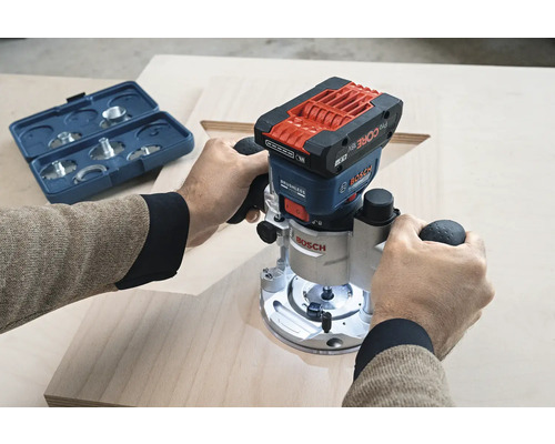 O persoană folosește o freză verticală Bosch pe o scândură de lemn. Un set de freze se află în apropiere.