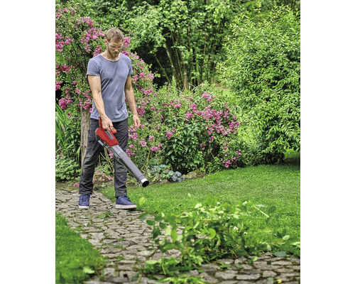 Un bărbat folosește un aspirator de frunze în grădină pentru a îndepărta frunzele și deșeurile de grădină.