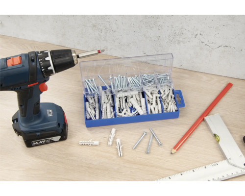 Șurubelniță cu acumulator, sortiment de șuruburi și dibluri pe o suprafață de lucru