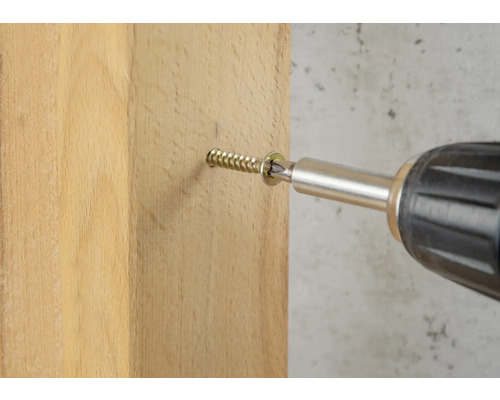 Un șurub este înșurubat într-o scândură de lemn cu o șurubelniță electrică.